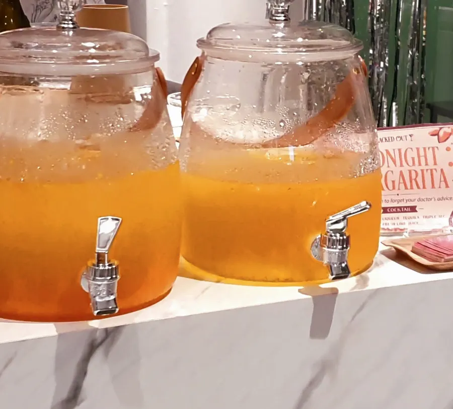 Two glass dispensers of an orange drink on a marble counter
